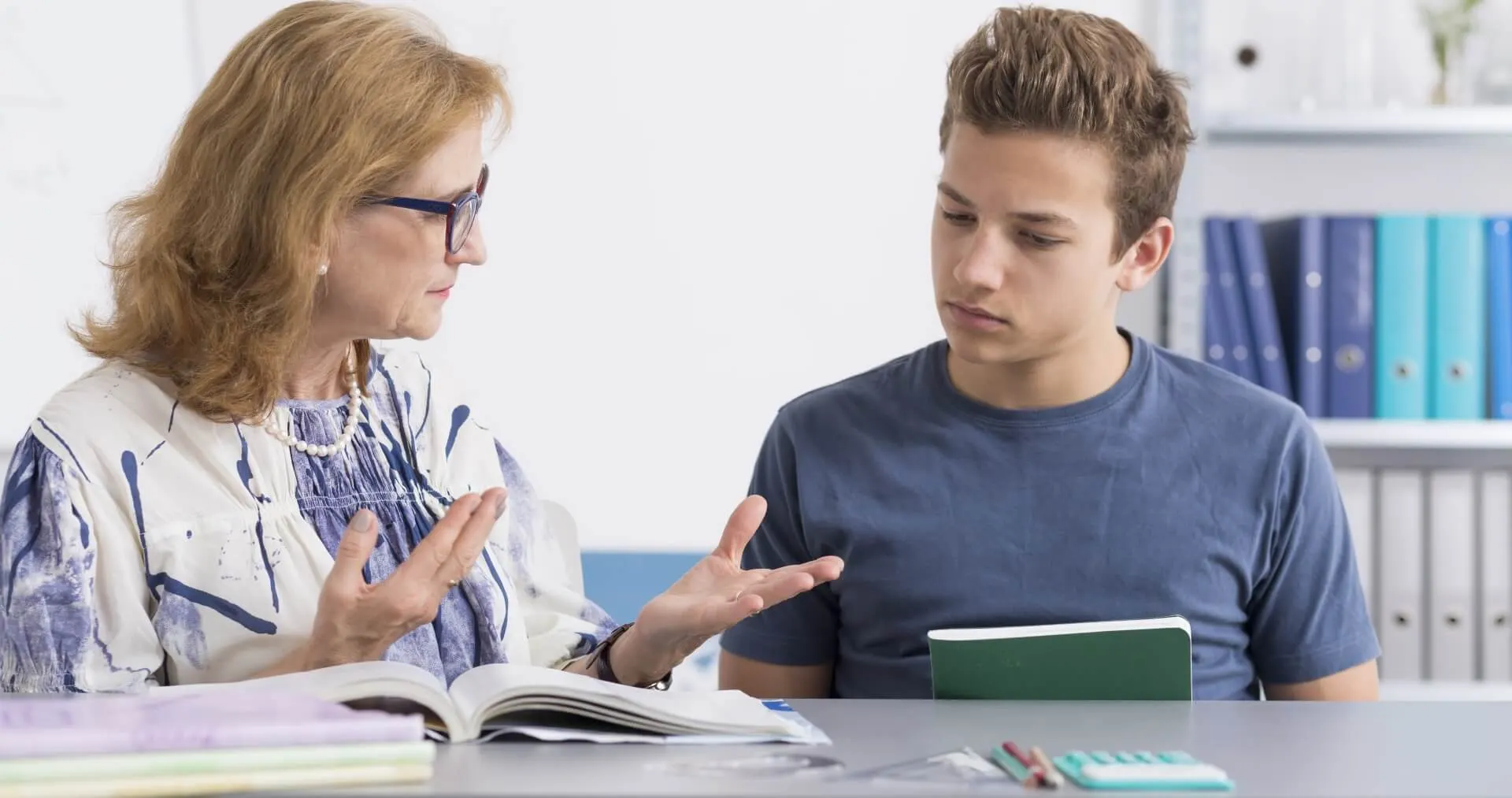 Een docent legt de lesstof uit aan een leerling